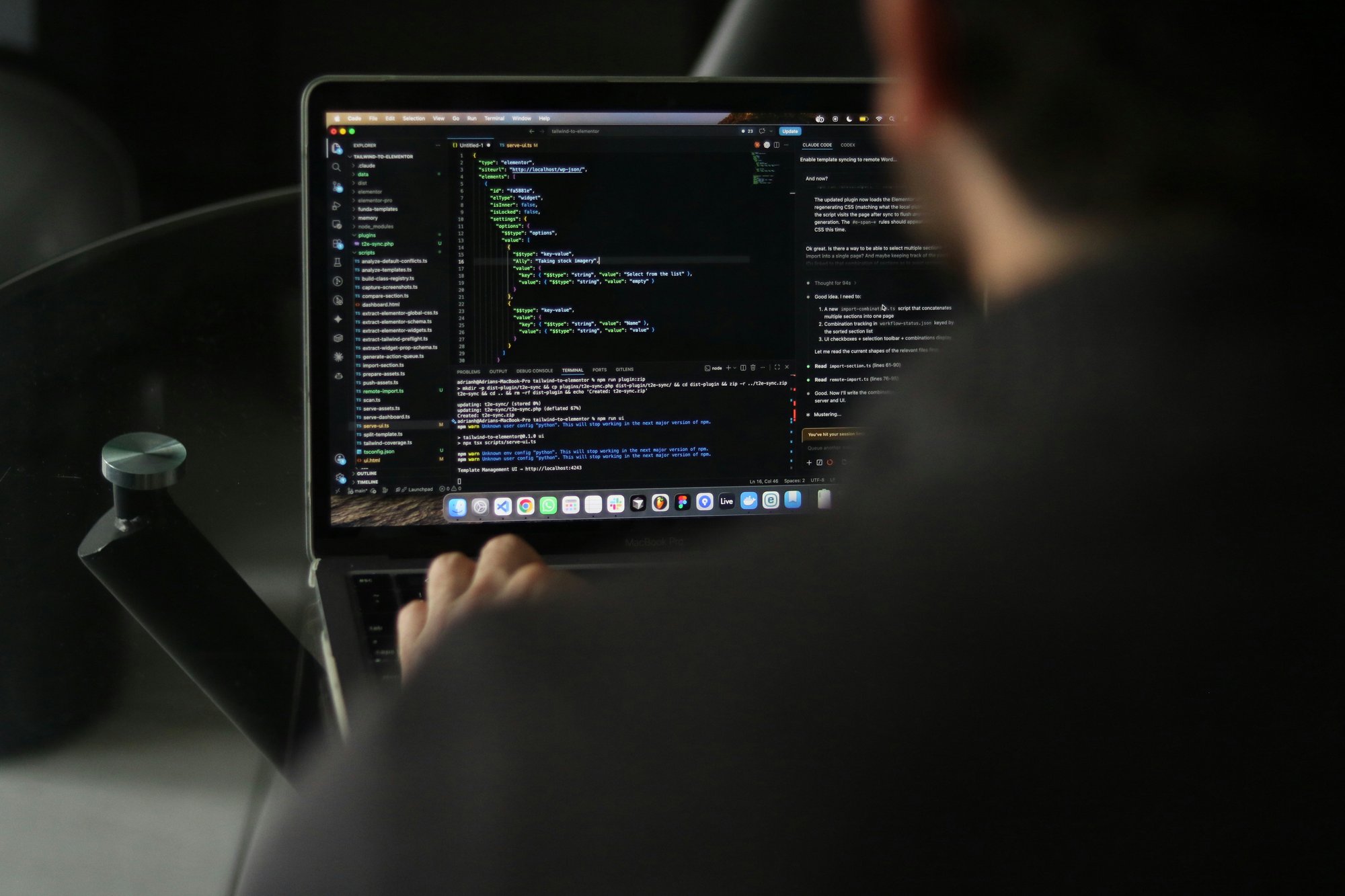 Software developer typing code on a laptop while working at a computer